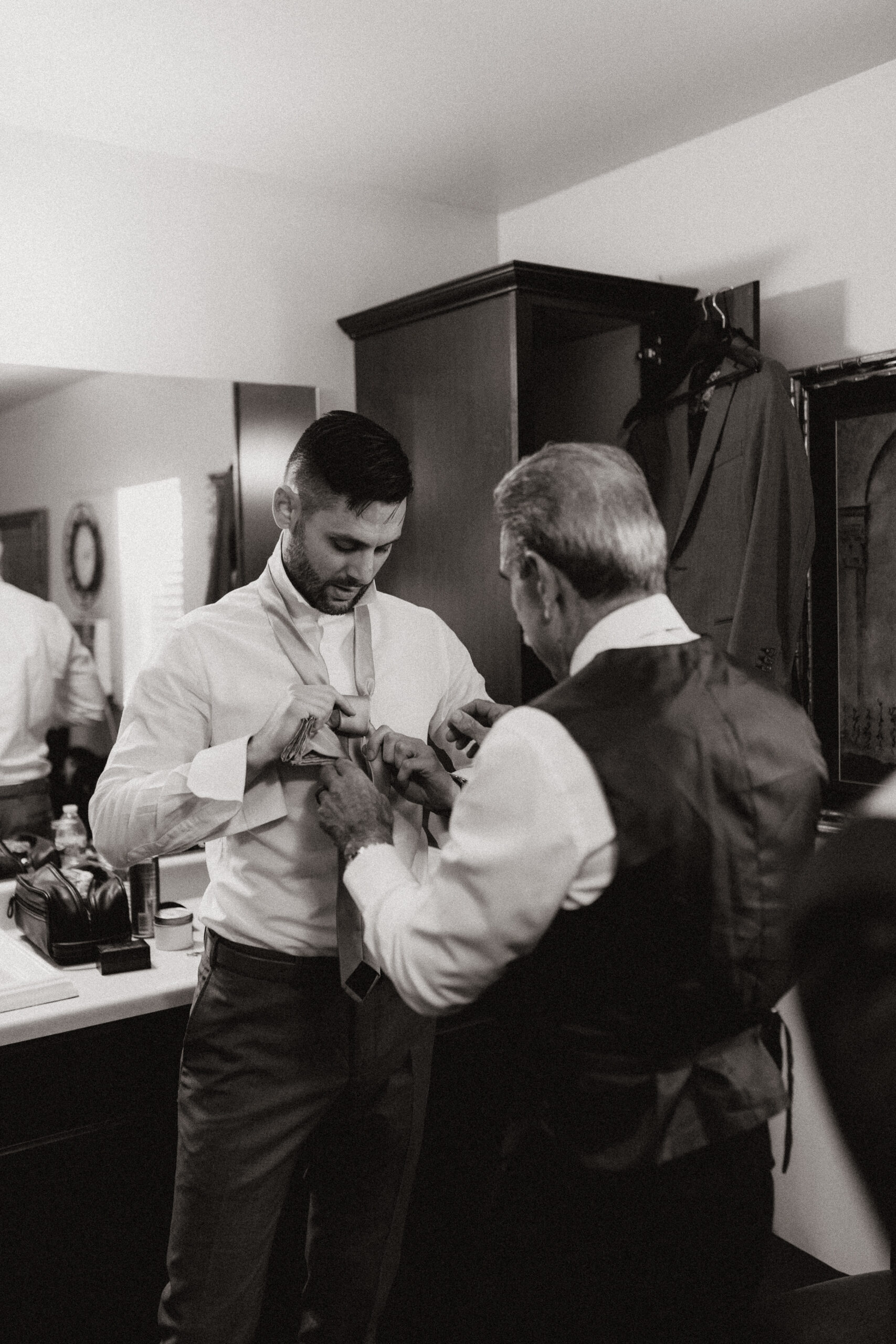 groom getting help with his tie at wright house wedding