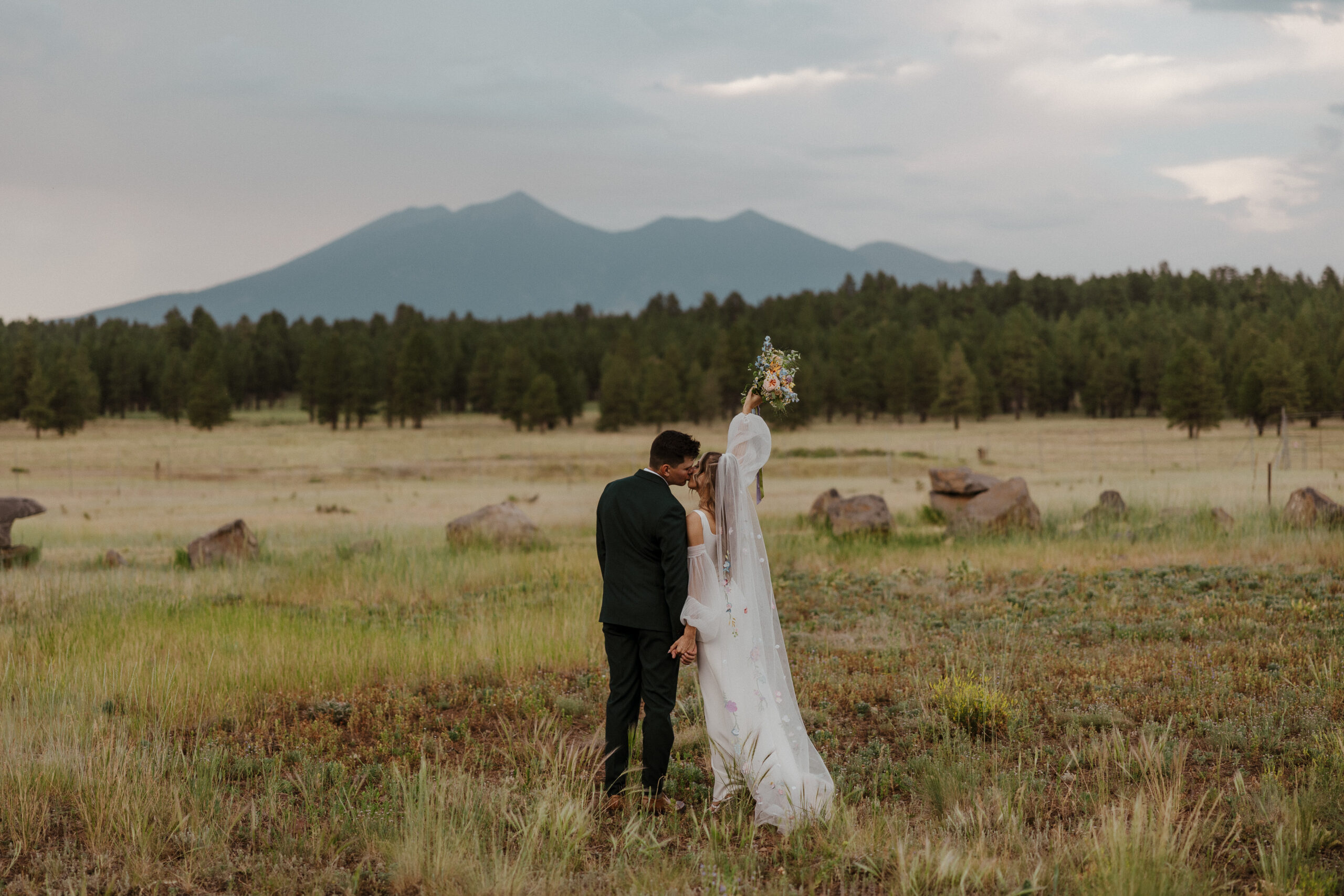bridal couple kissing against gorgeous mountain and forest backdrop