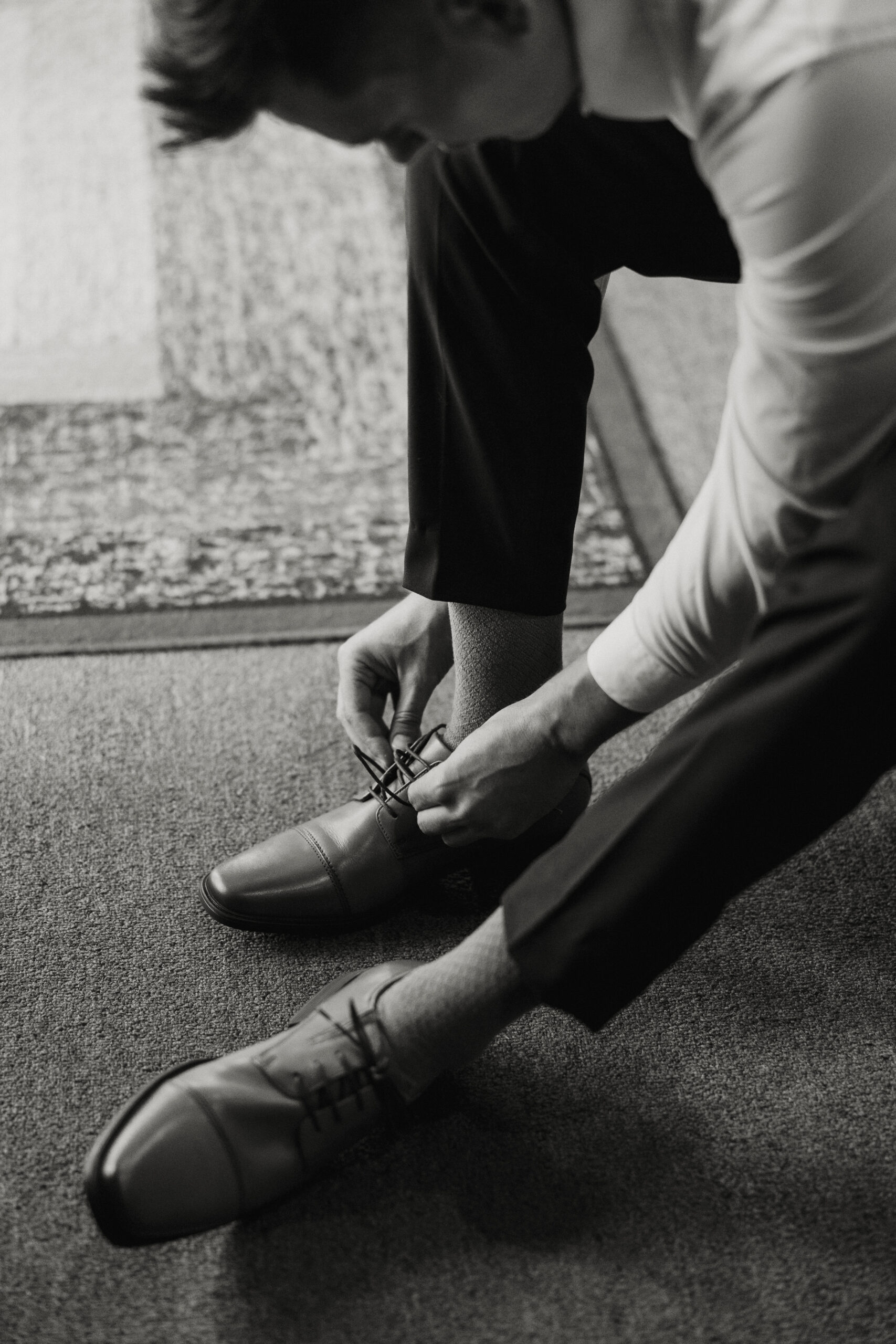 groom tying his shoes for intimate forest wedding 