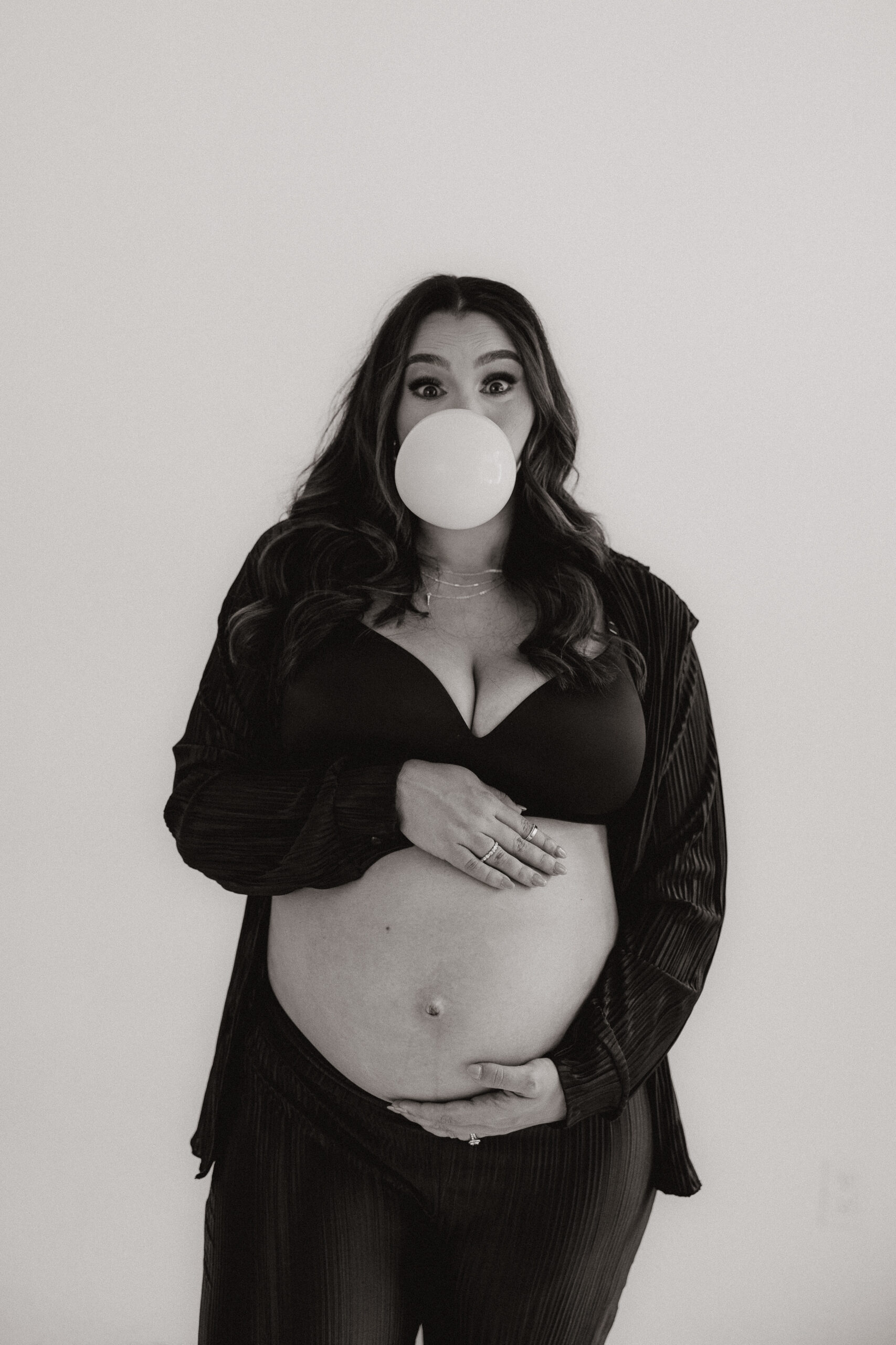 pregnant woman blowing a bubble and holding her stomach 