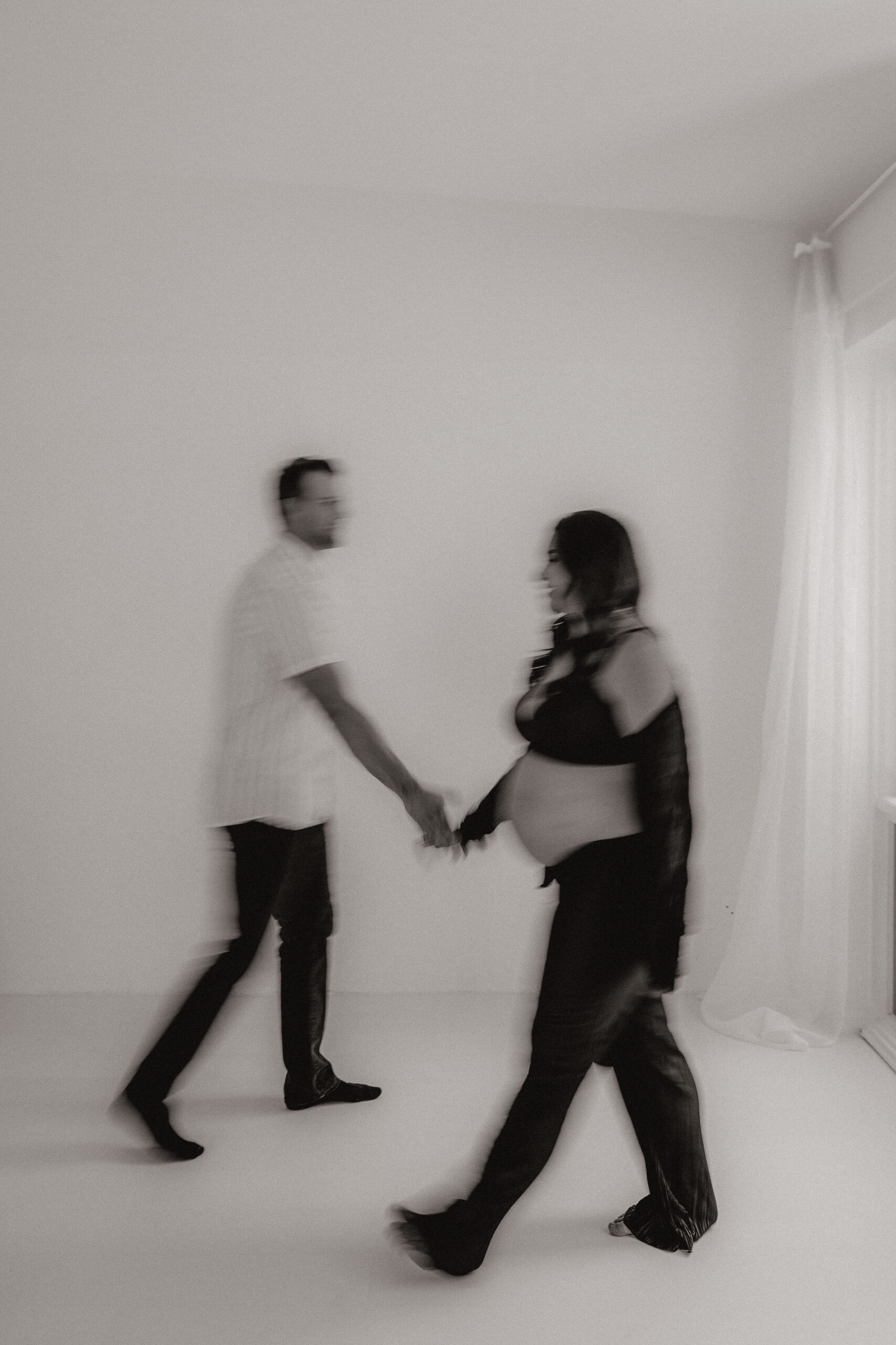 a blurry editorial maternity photo of the couple walking past each other 