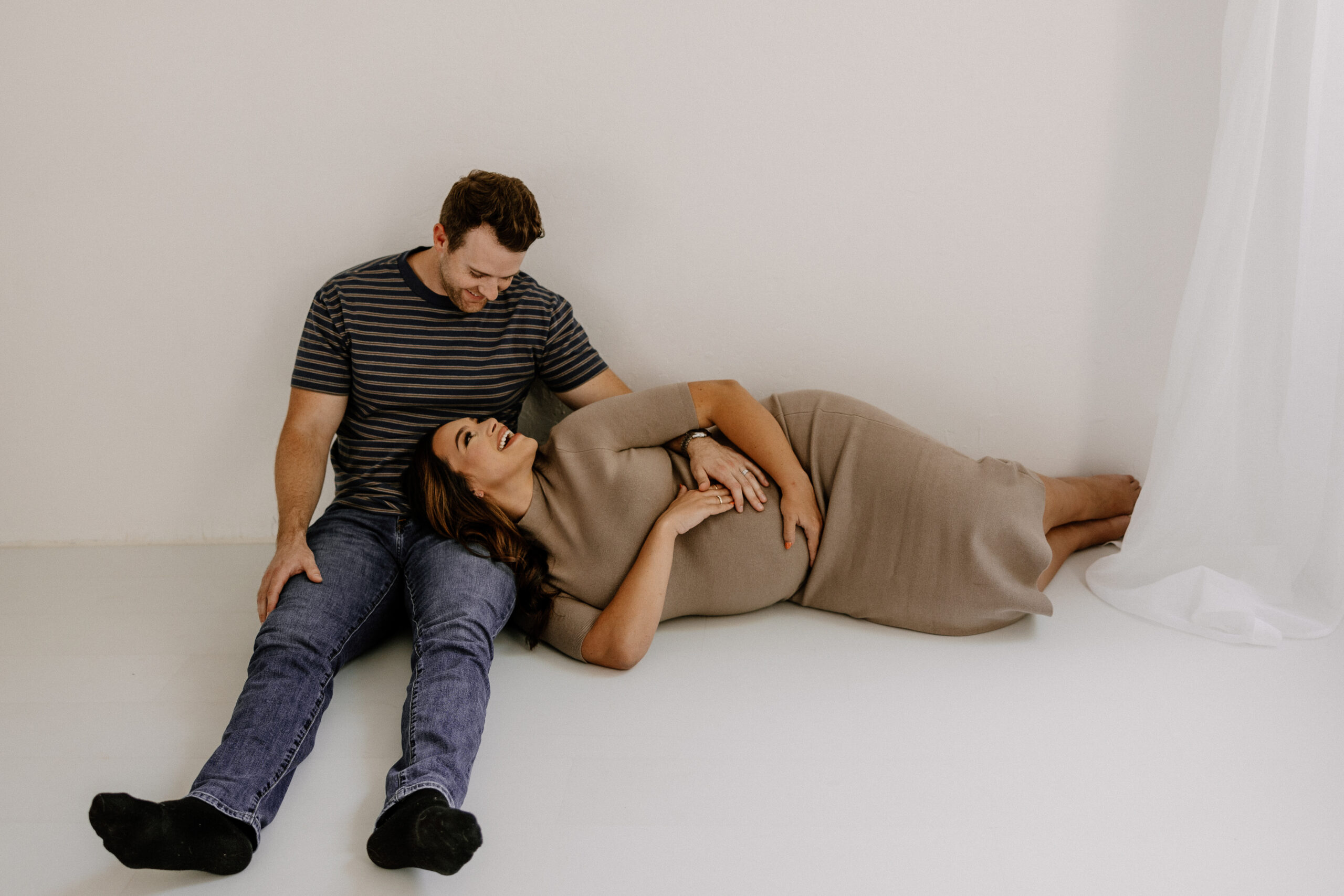 mom to be laying on the floor resting her head in dad to be's lap during editorial maternity photoshoot