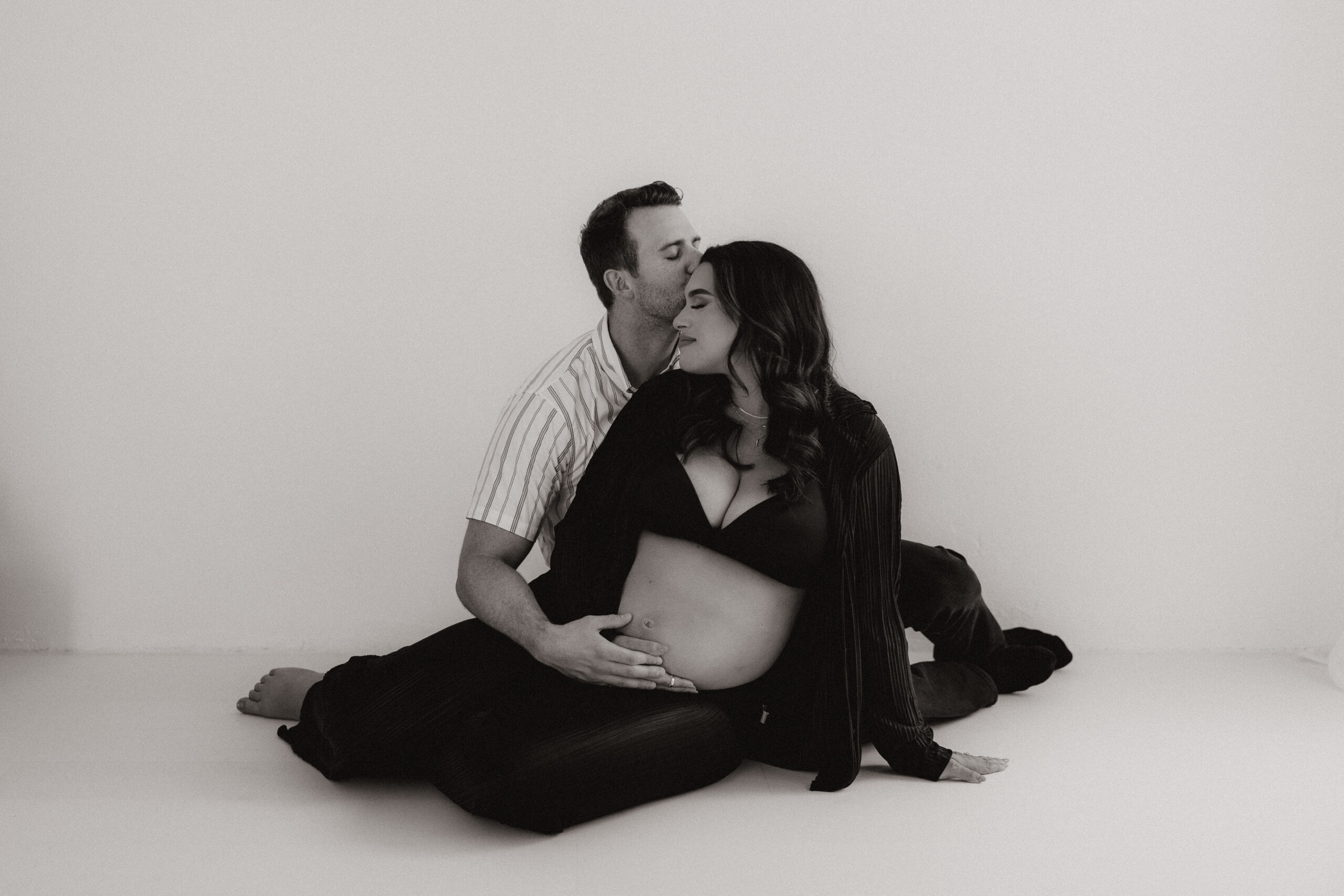 couple sitting on the floor of the studio together during their editorial maternity photoshoot