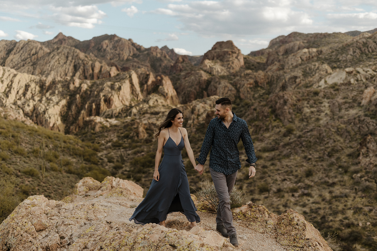 couple holding hands and walking in the mountains during canyon lake arizona engagement pictures