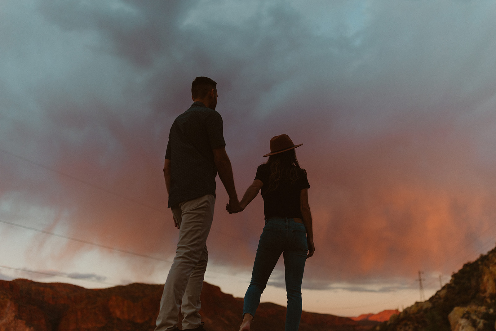 couple holding hands and facing away from the camera at sunset at canyon lake 