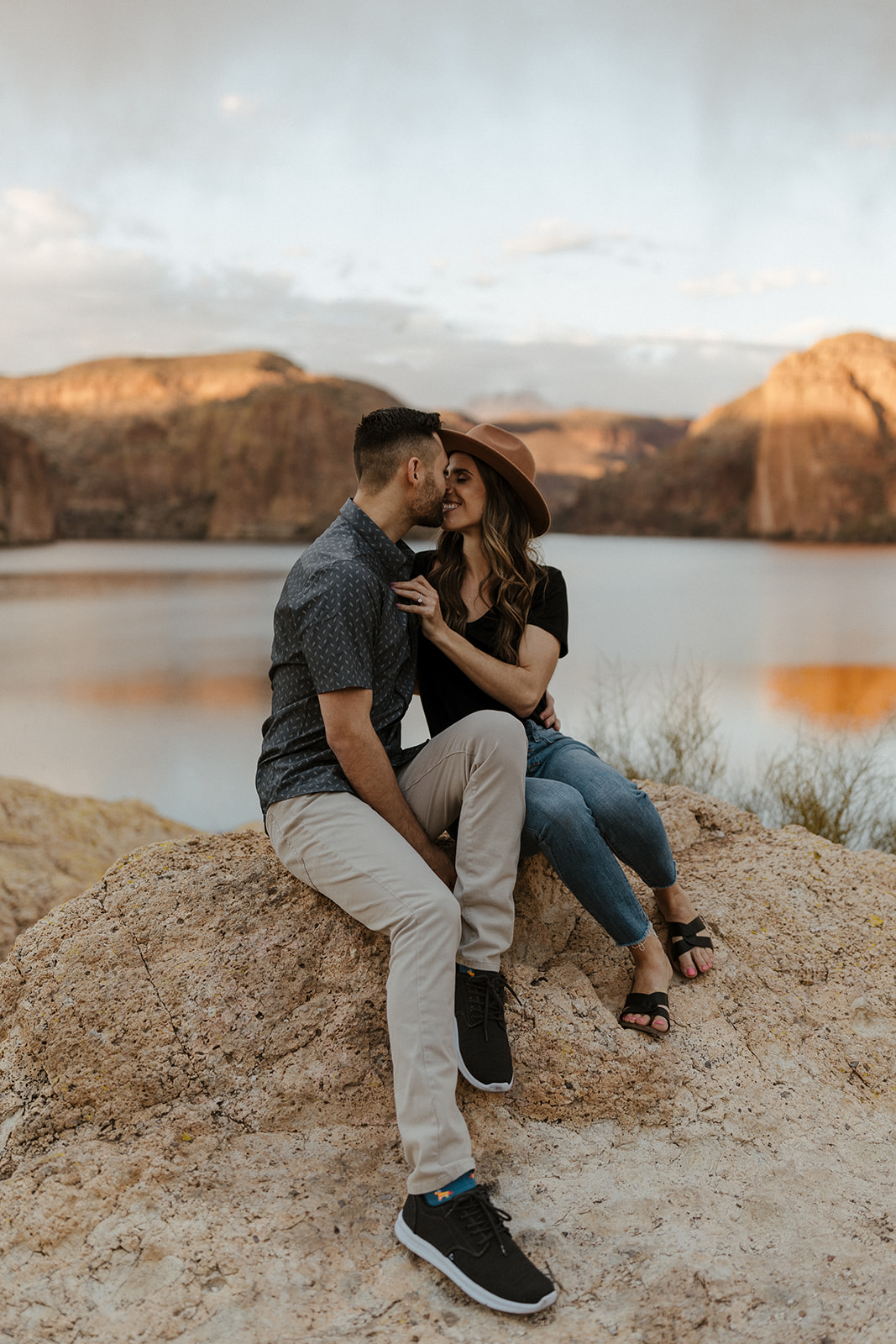 couple kissing on a rock by the lake during canyon lake arizona engagement pictures
