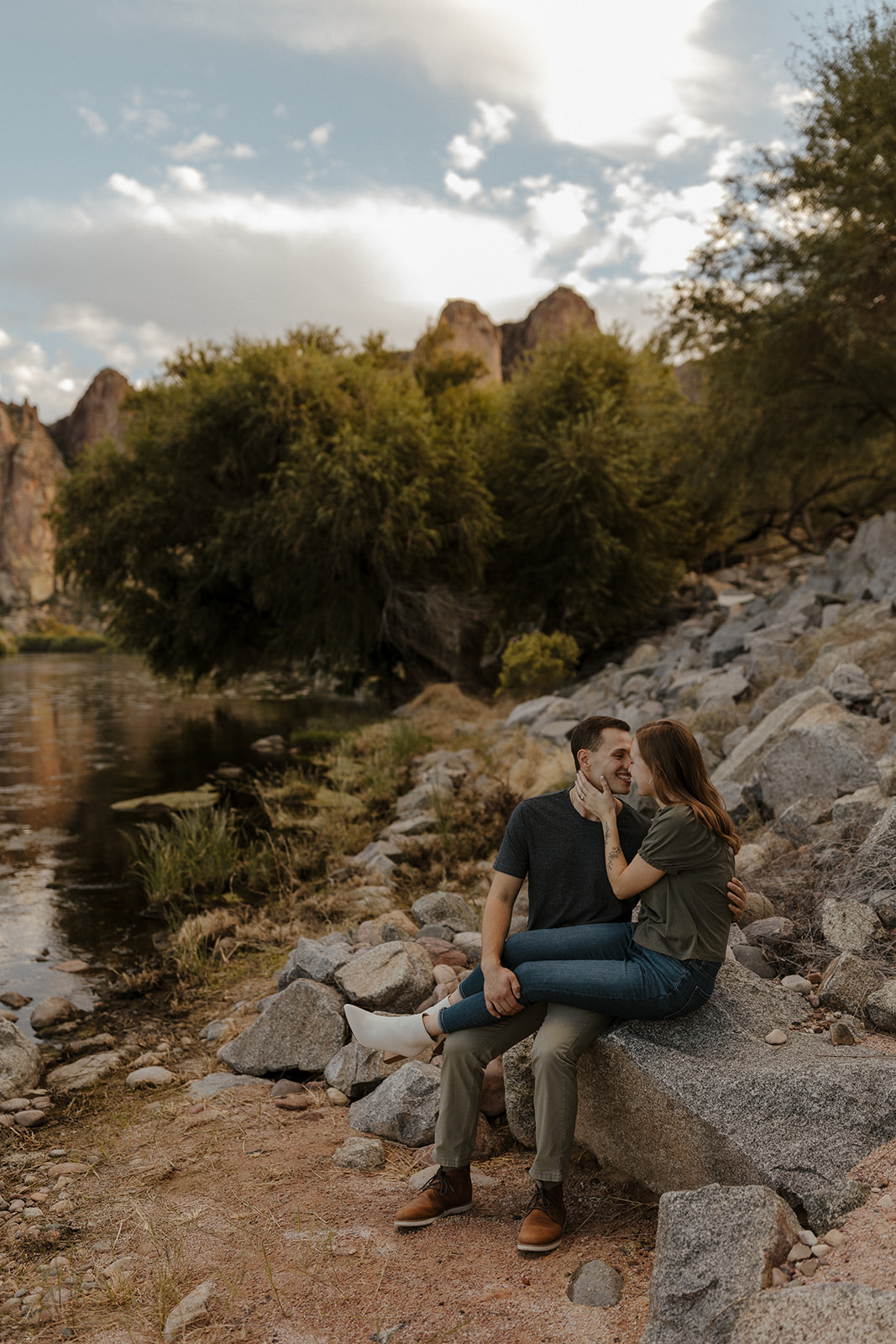 newly engaged couple sitting on the rocks by the river at saguaro lake guest ranch Arizona for their engagement session