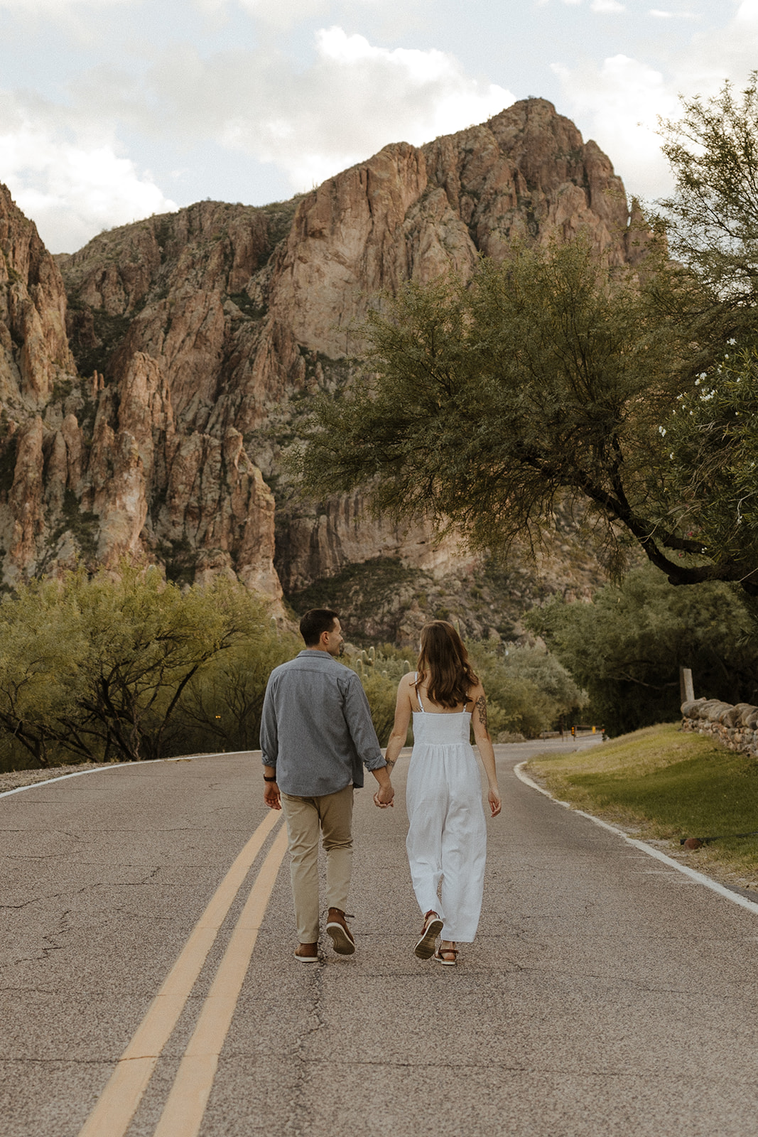 newly engaged couple holding hands and walking away on the road at saguaro lake guest ranch Arizona 