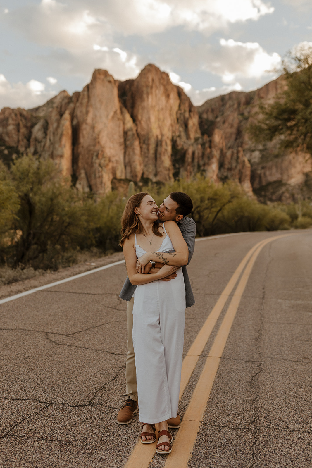 newly engaged couple holding each other on the road with mountain scenery in the background 