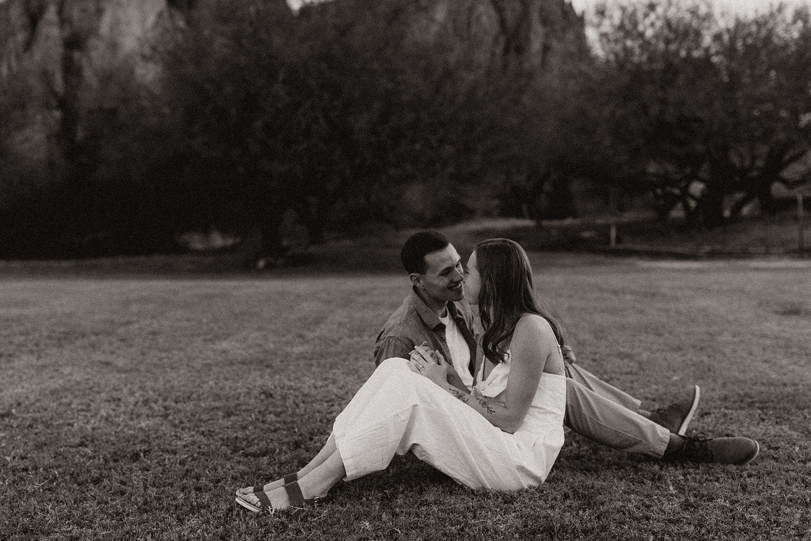 newly engaged couple sitting on the grass looking at each other at saguaro lake guest ranch Arizona 