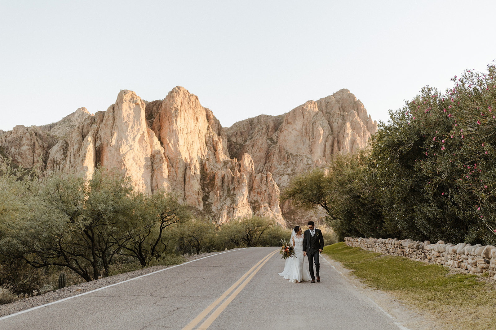 wedding couple walking on a road with mountains behind them at Saguaro Lake Guest Ranch Wedding