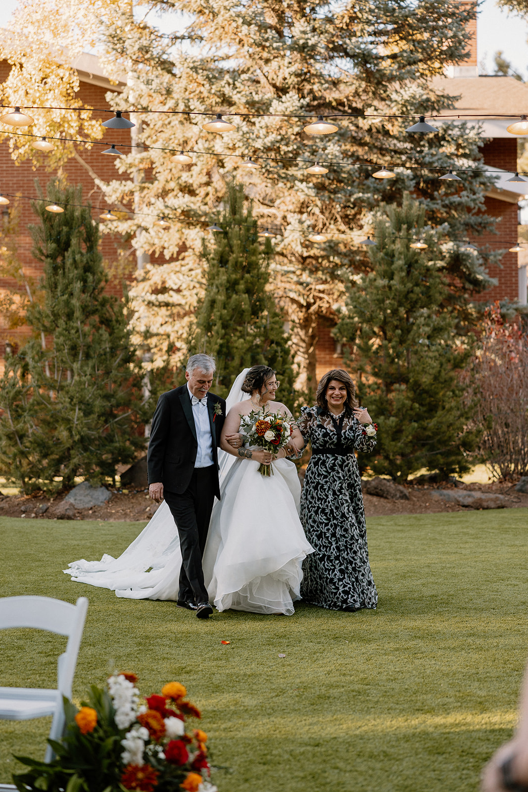 Bride gets walked into her ceremony by her father and mother