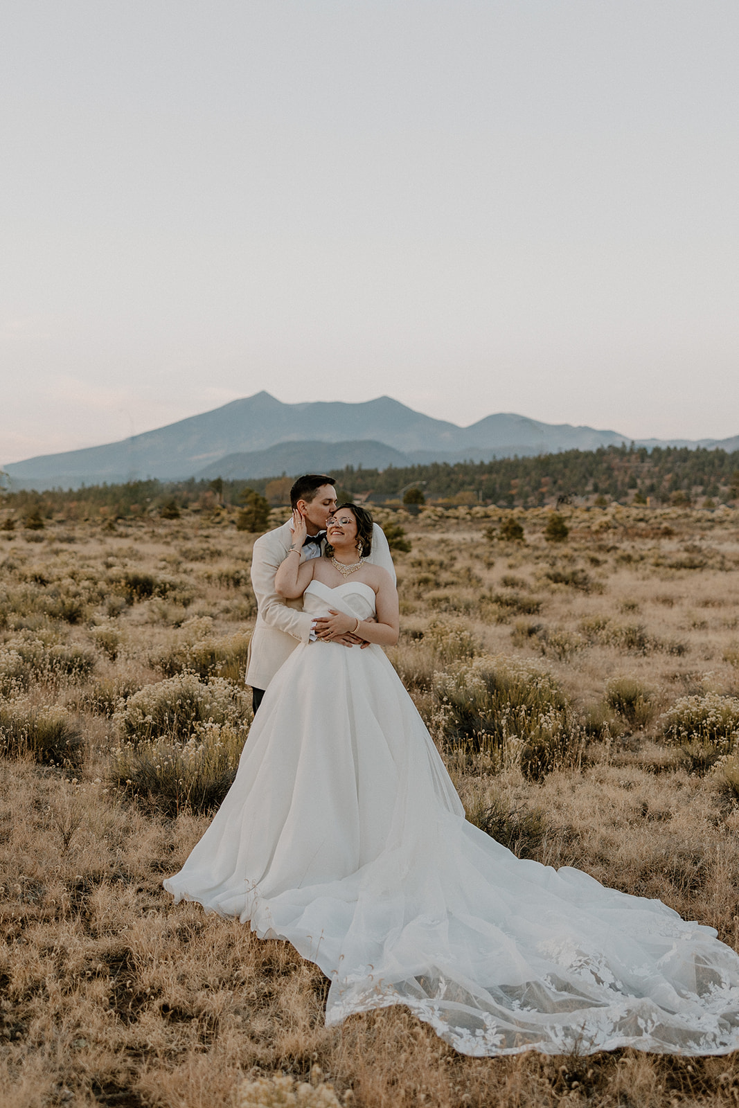 Stunning bride and groom pose together with the Arizona mountains in the background
