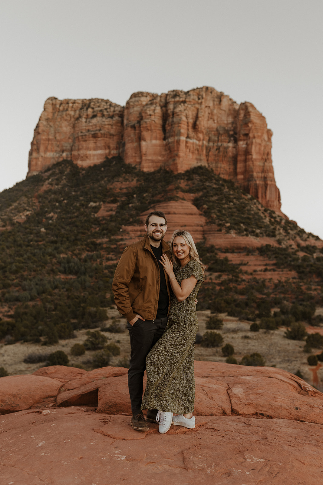 engaged couple standing together with red mountains behind them for sedona engagement photos