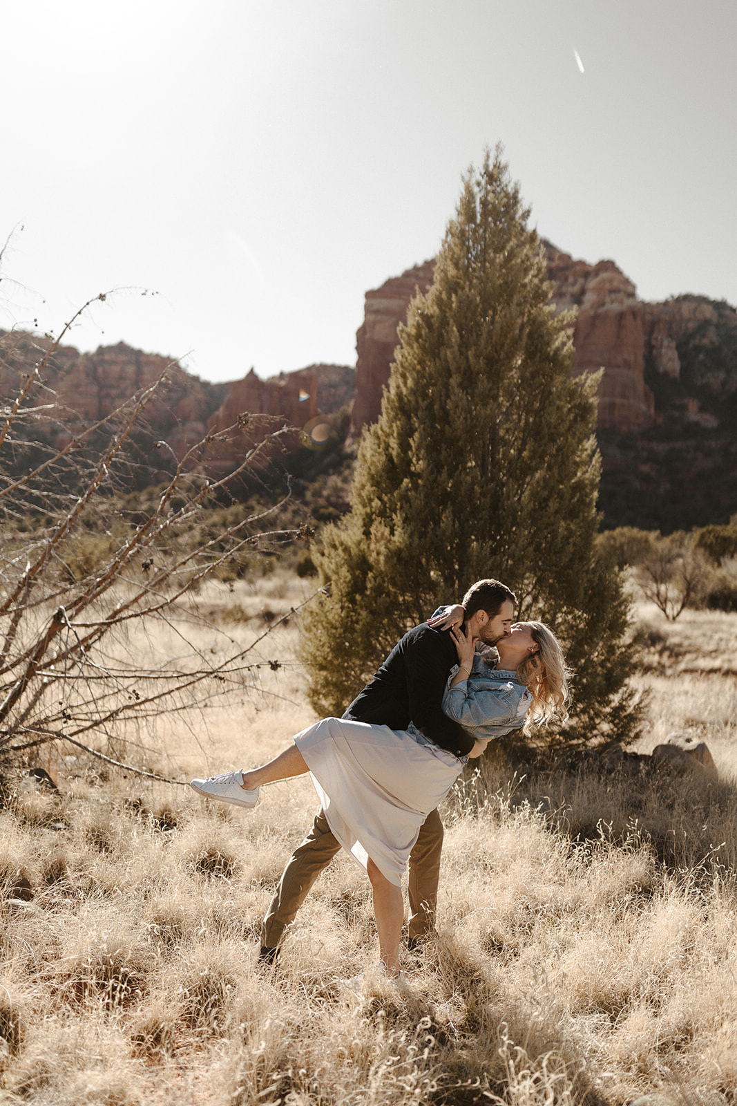 engaged couple kissing in the dry grass during sedona engagement photos