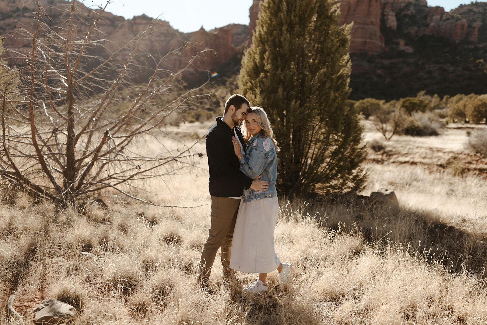 engaged couple holding each other in the dry grass during sedona engagement photos