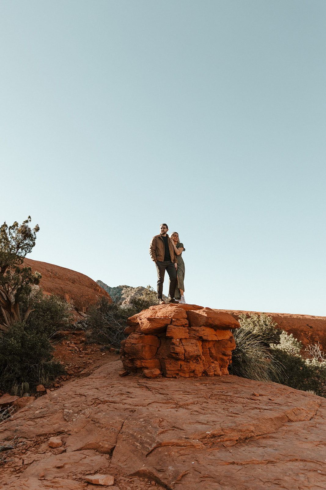 couple standing on red rocks with the blue sky above them during sedona engagement photos