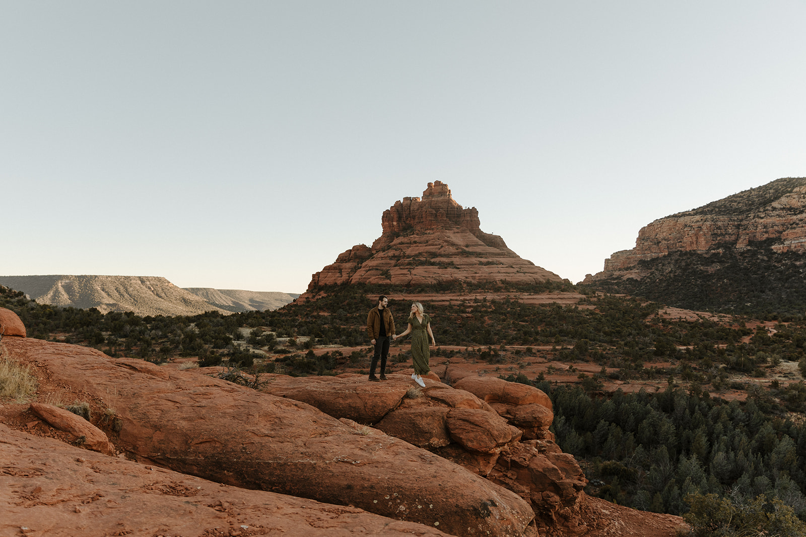 engaged couple standing on red rocks during sedona engagement photos