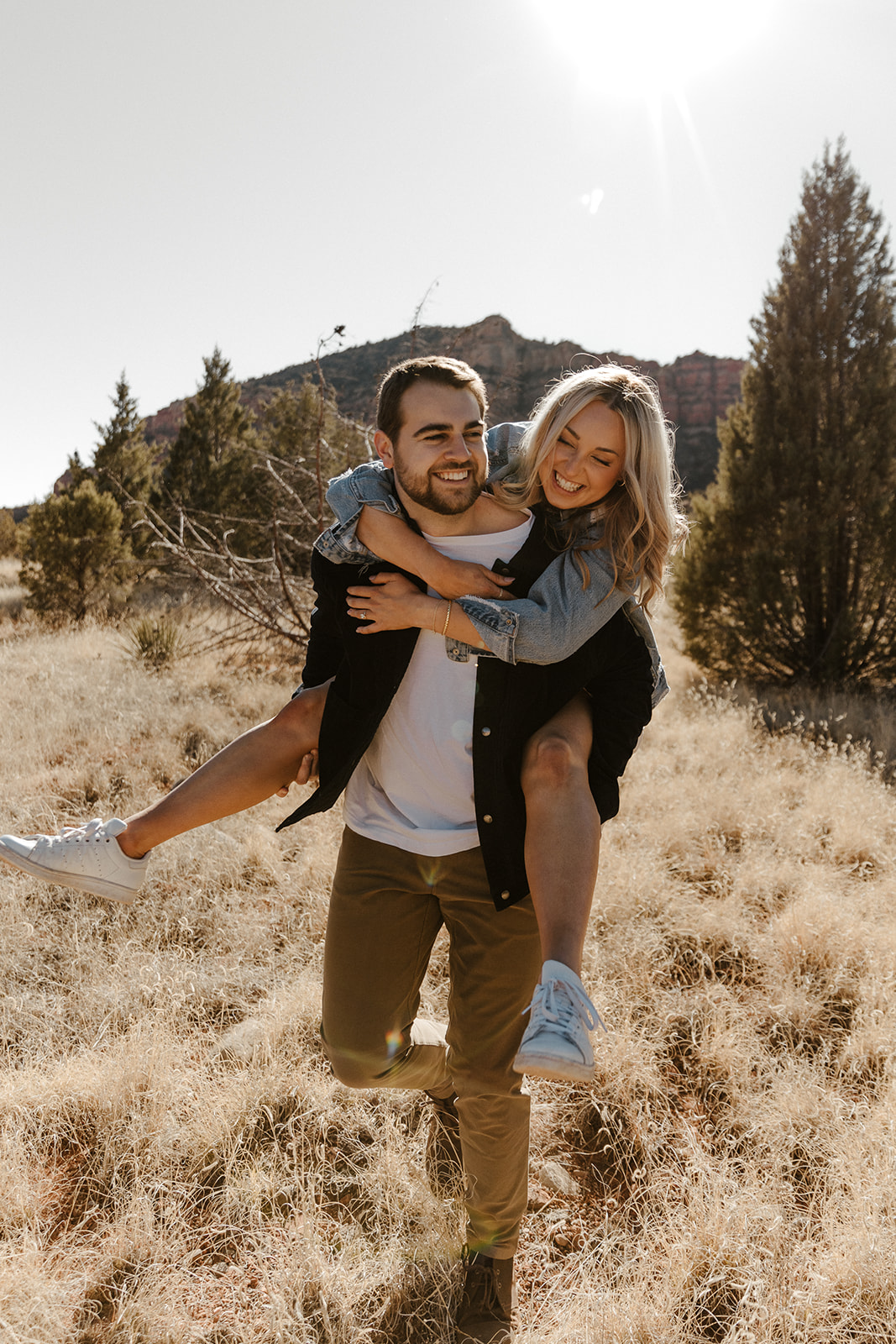 fiance on other fiances back while they laugh together during sedona engagement photos