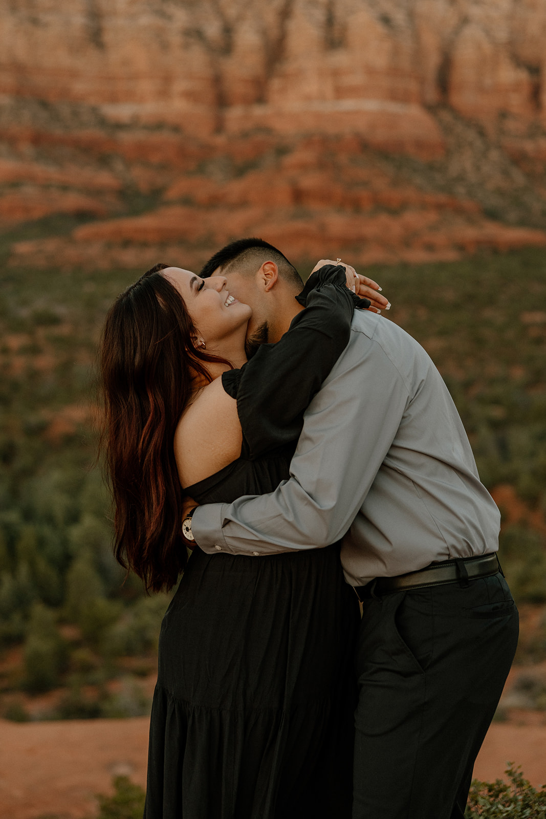 Stunning couple share a hug with the beautiful Arizona nature in the backdrop during their dreamy west fork trail in Sedona Arizona engagement photoshoot 