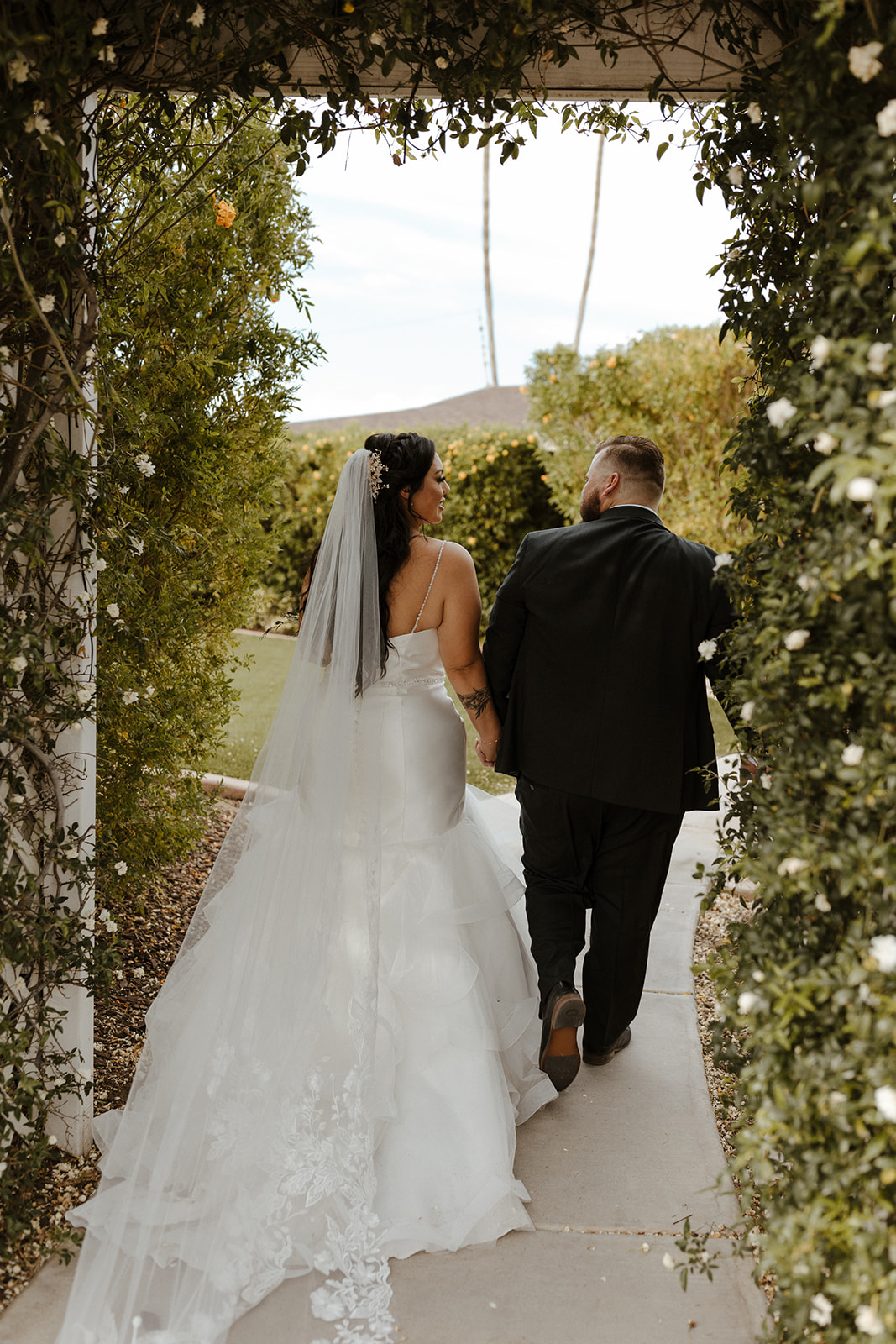 Bride and groom walk through the beautiful floral arch 