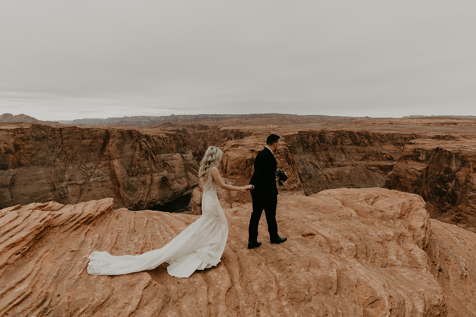 stunning bride and groom pose with the canyon in the background
