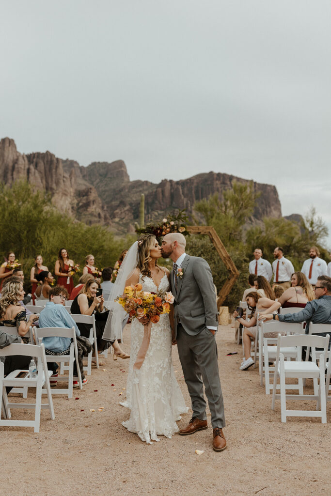 stunning bride and groom share a kiss as they exit their dreamy lost dutchman state park wedding