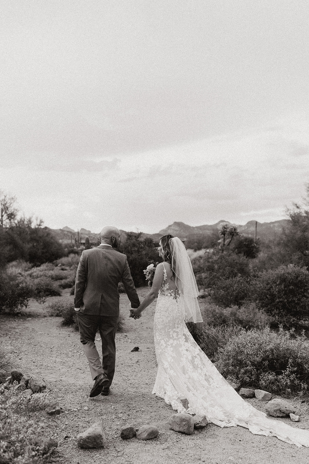 bride and groom walk together into the Arizona nature