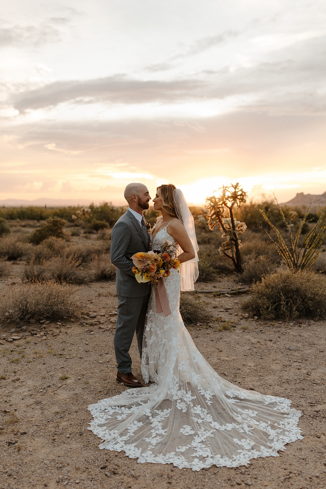 bride and groom pose as the sun goes down after their wedding at lost dutchman state park