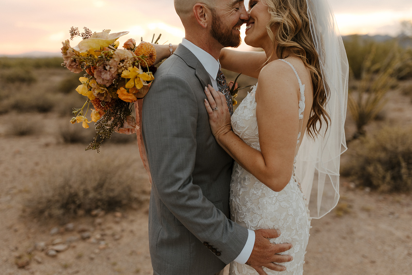 bride and groom share a kiss as the sun dips below the horizon on their lost dutchman state park wedding day