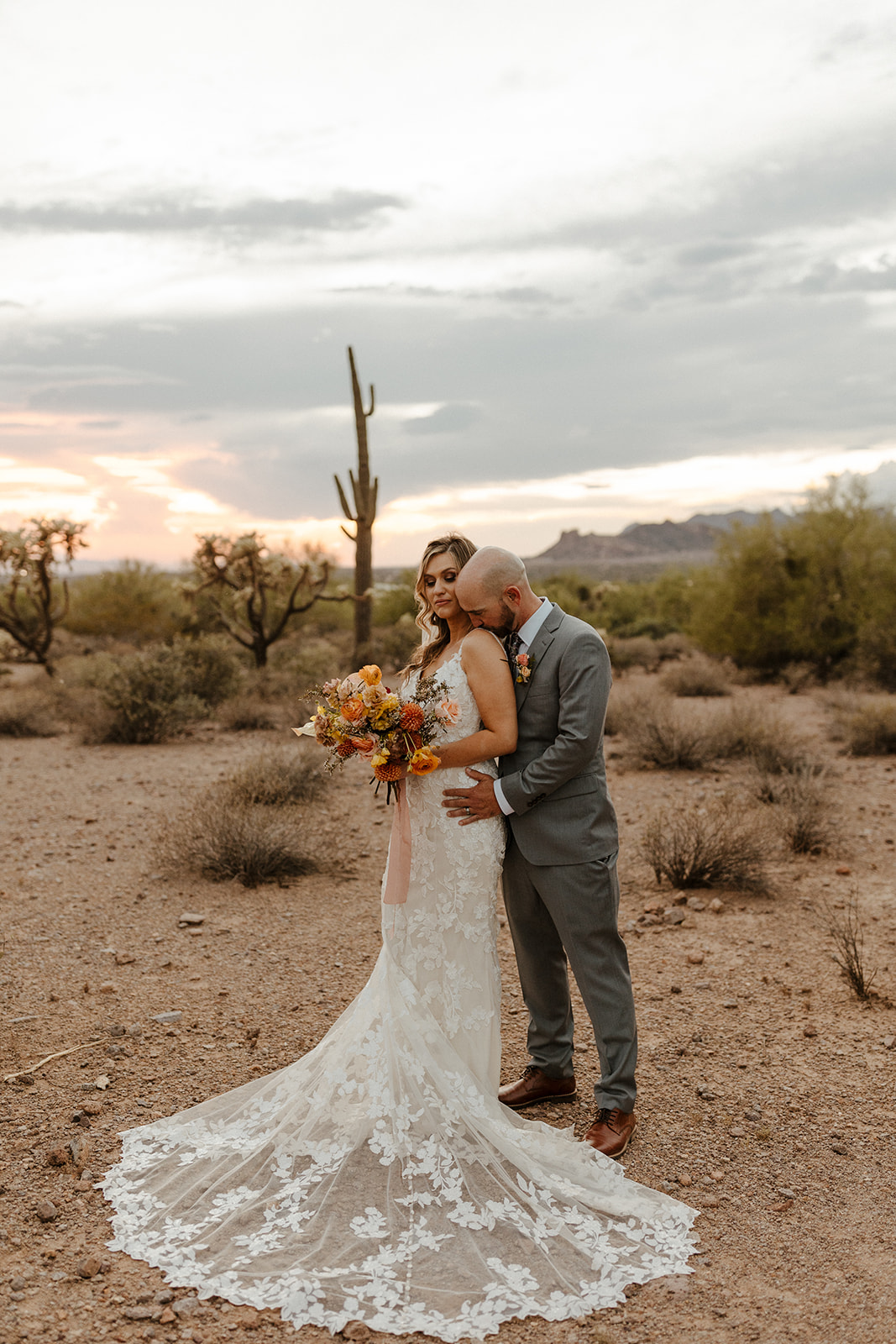 Beautiful bride and groom pose in front of a full grown cactus in lost dutchman state park