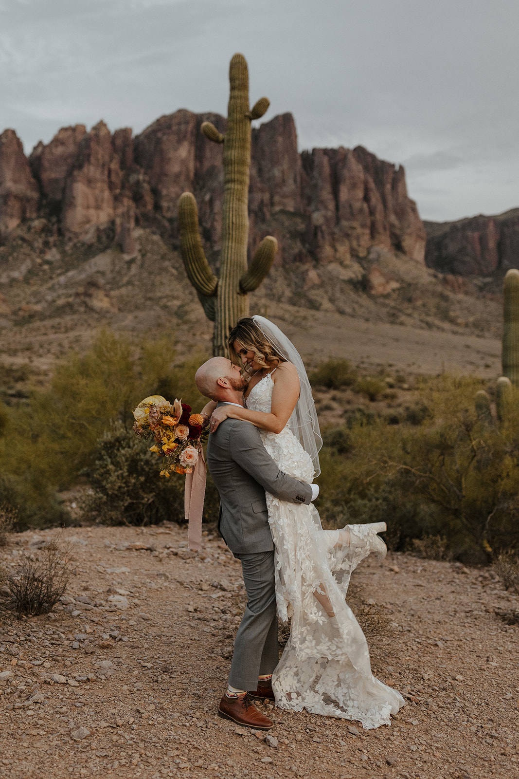 Bride jumps into her new husbands arms as they pose in front a beautiful cactus