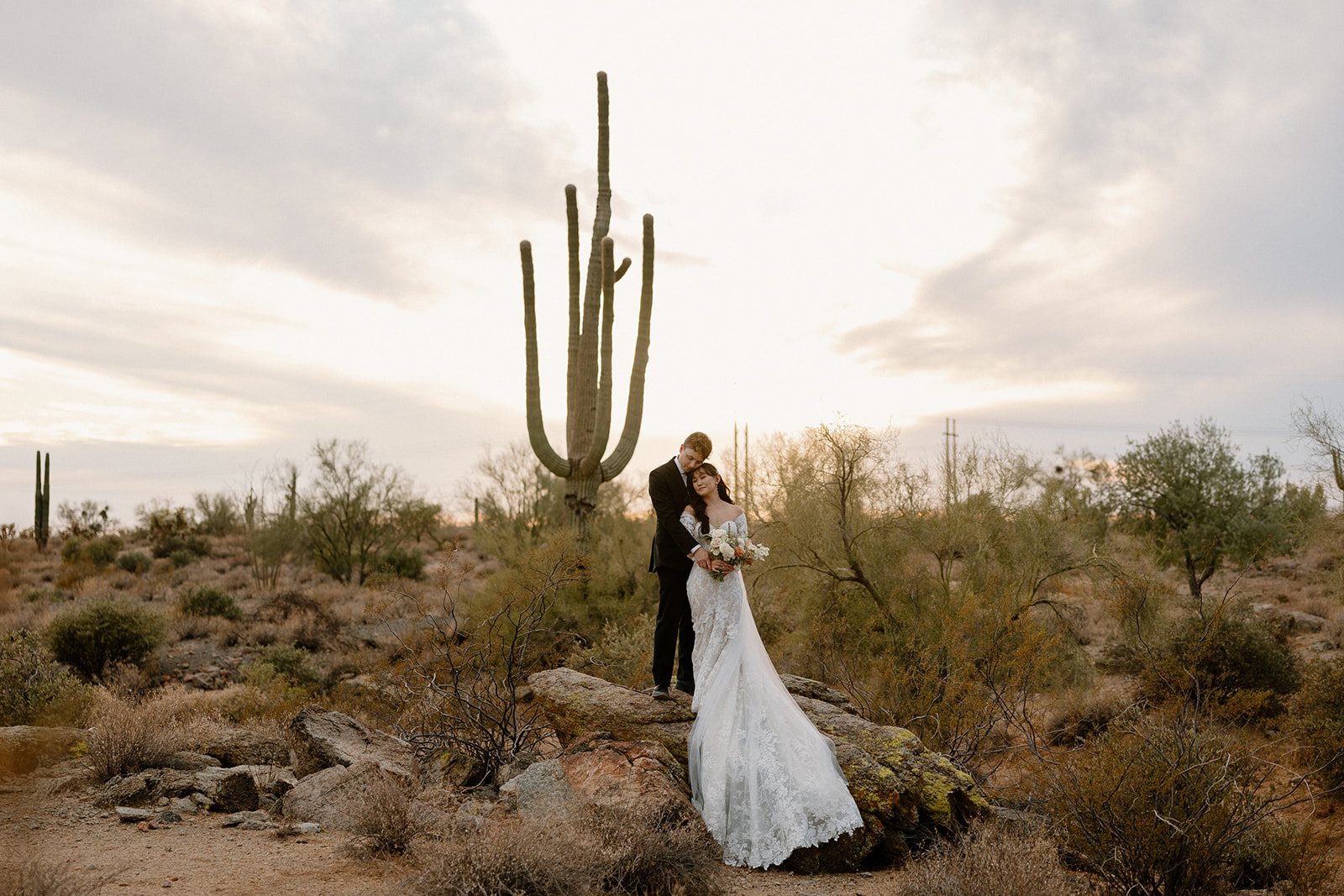 stunning bride and groom pose in front of a cactus in the boho desert wedding at the Paseo