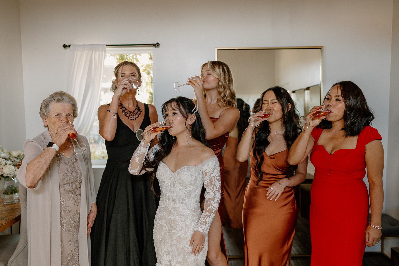 Bride and her wedding party drinks a glass of wine in preparation for her stunning wedding day
