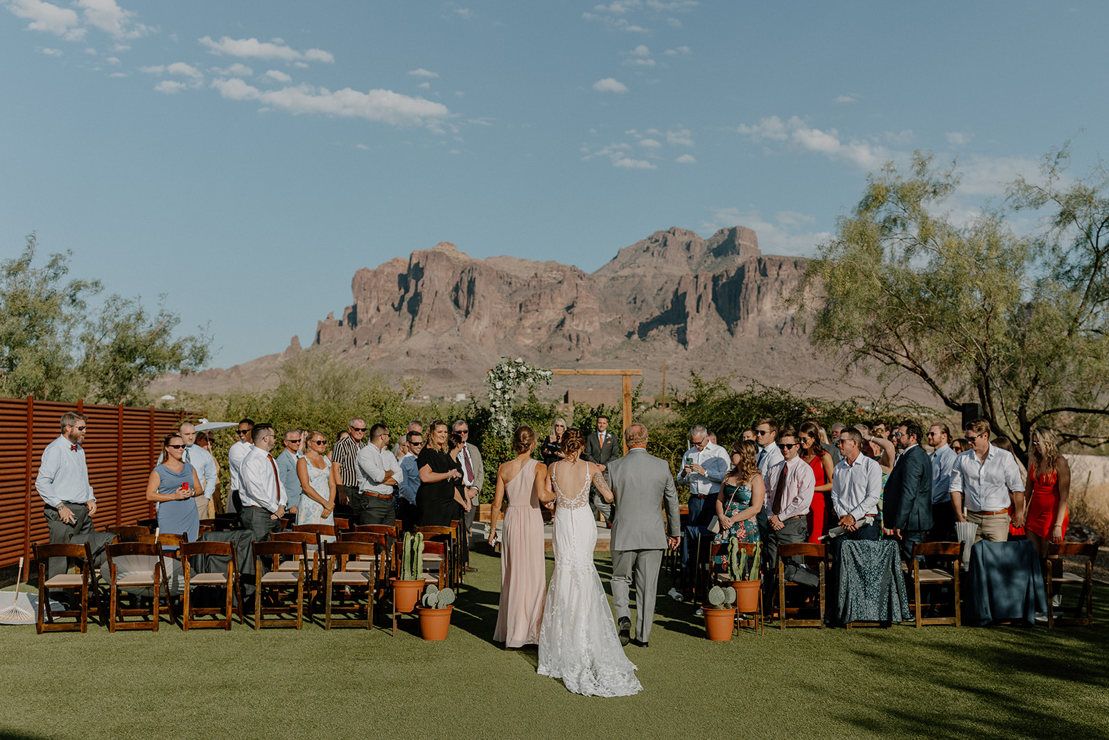 bride gets escorted down the aisle by her mom and dad with the beautiful Arizona nature in the background