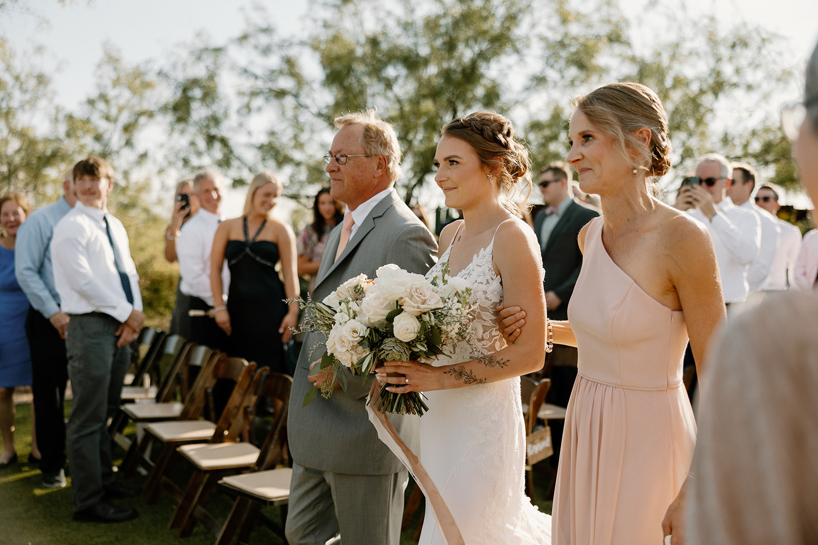 bride gets escorted down the aisle by her mom and dad