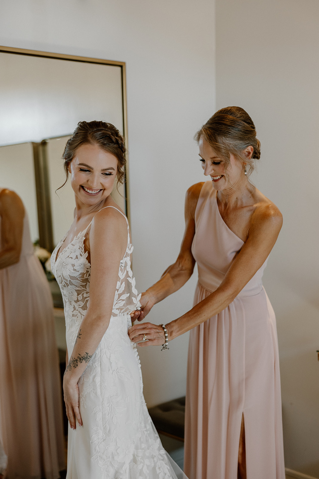 Stunning bride gets help zipping her elegant wedding dress