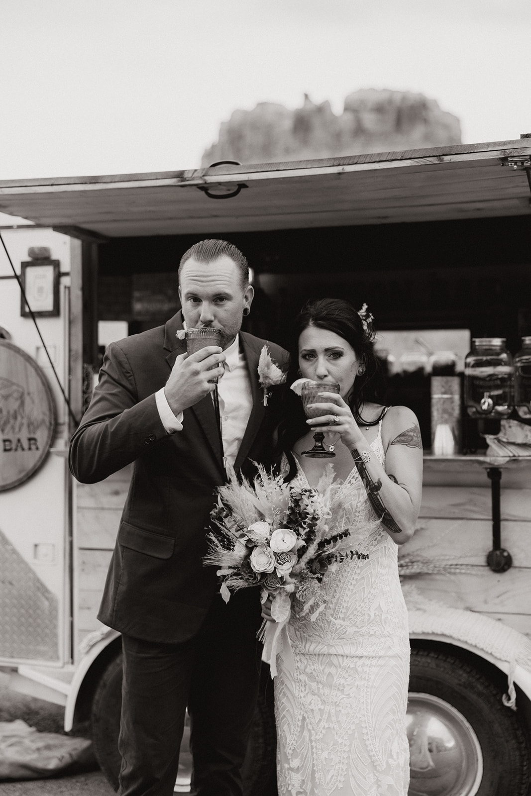 bride and groom sip their drinks from the mobile bar