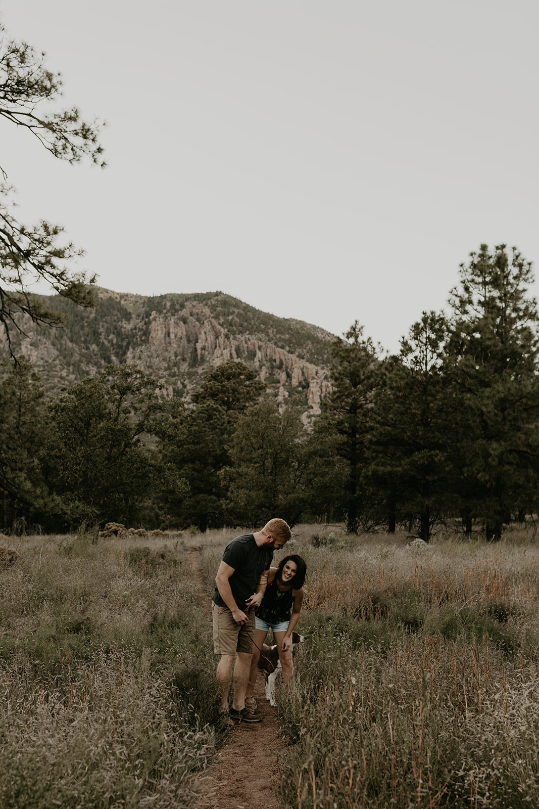 husband and wife pose together in the beautiful Arizona nature with their dog 