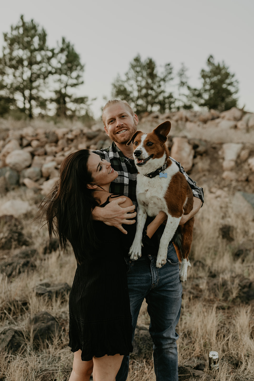 husband holds dog and gives his wife a big hug in the beautiful Arizona nature