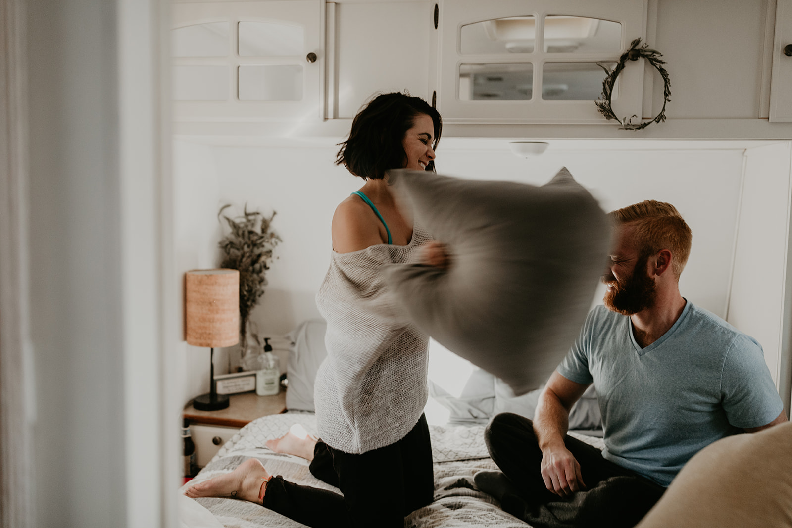 couple having a pillow fight during their in home couples photoshoot ideas