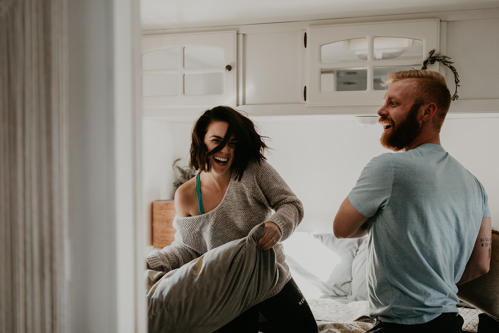 couple having a pillow fight during their in home couples photoshoot ideas