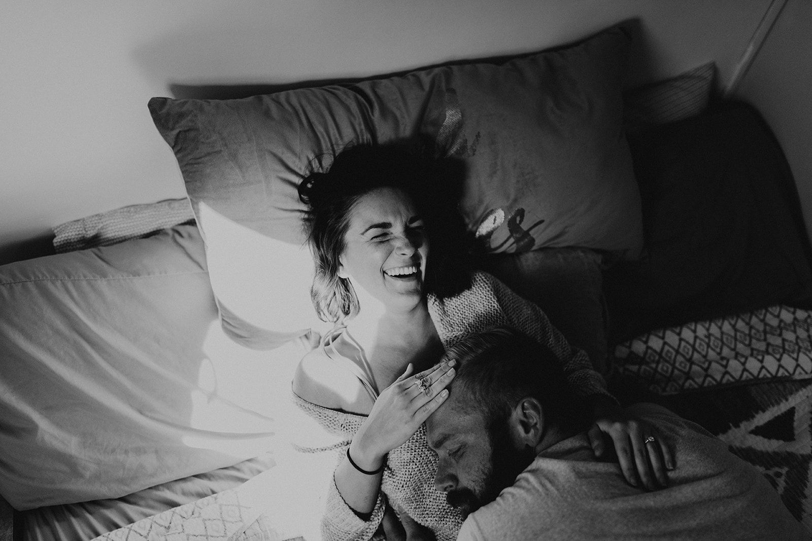 couple lies on the bed together during their in home couples photoshoot