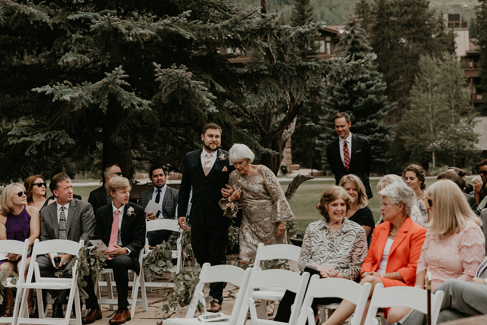 groom escorts his mom down the aisle to her seat before the ceremony