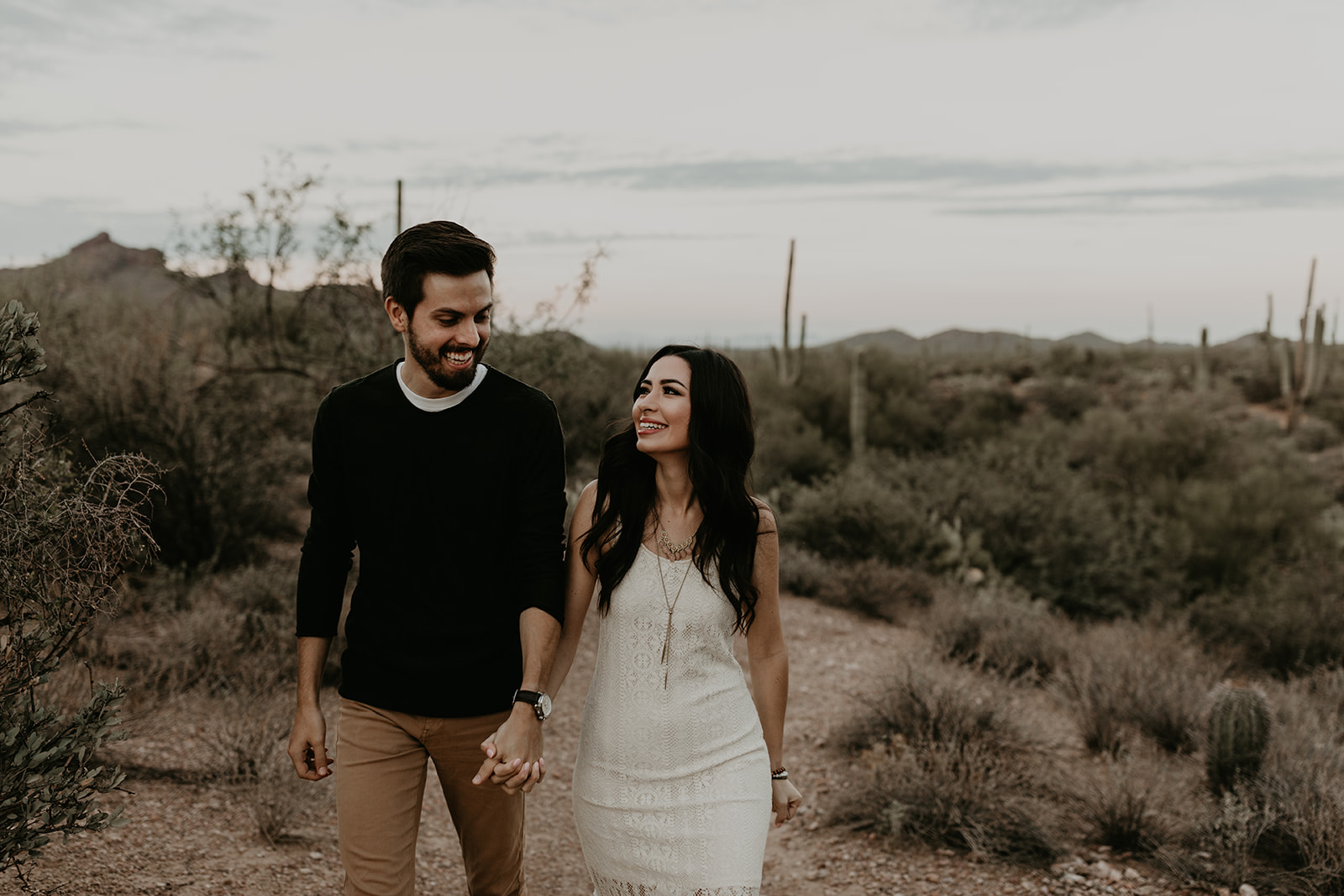 stunning couple walk together in the desert during their hiking engagement photos