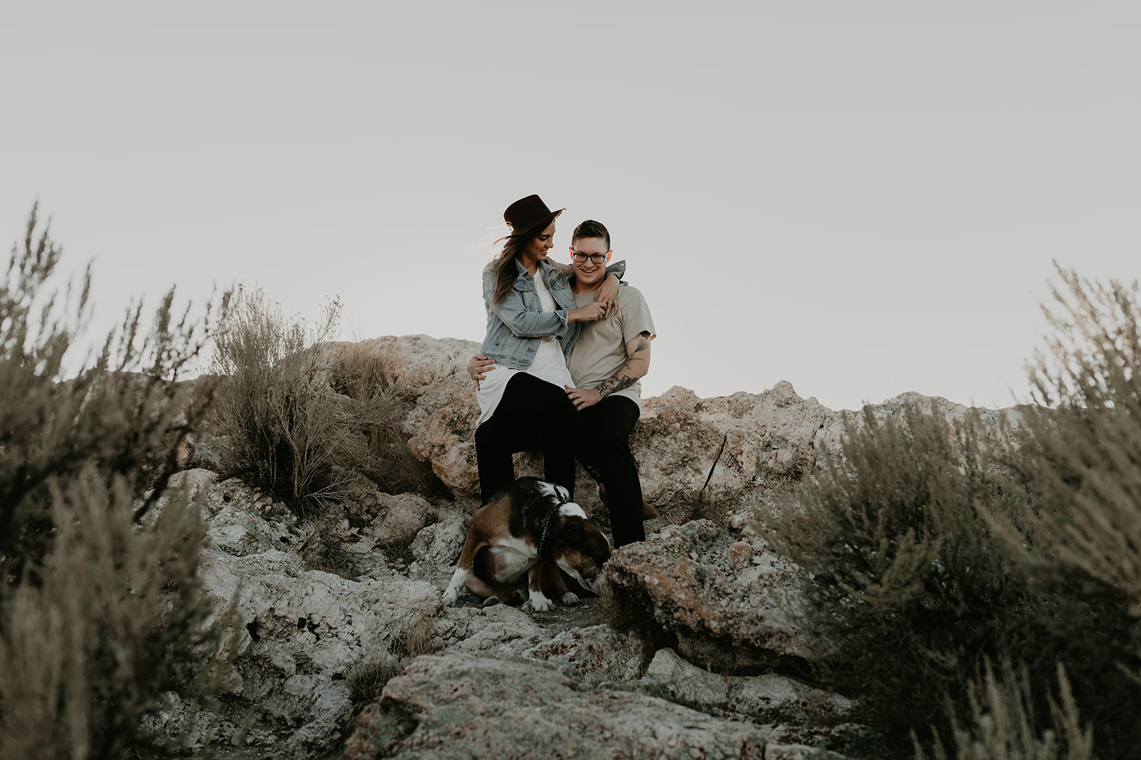 couple pose together with their dog on rocks in the beautiful Utah nature during their Engagement photos in Utah