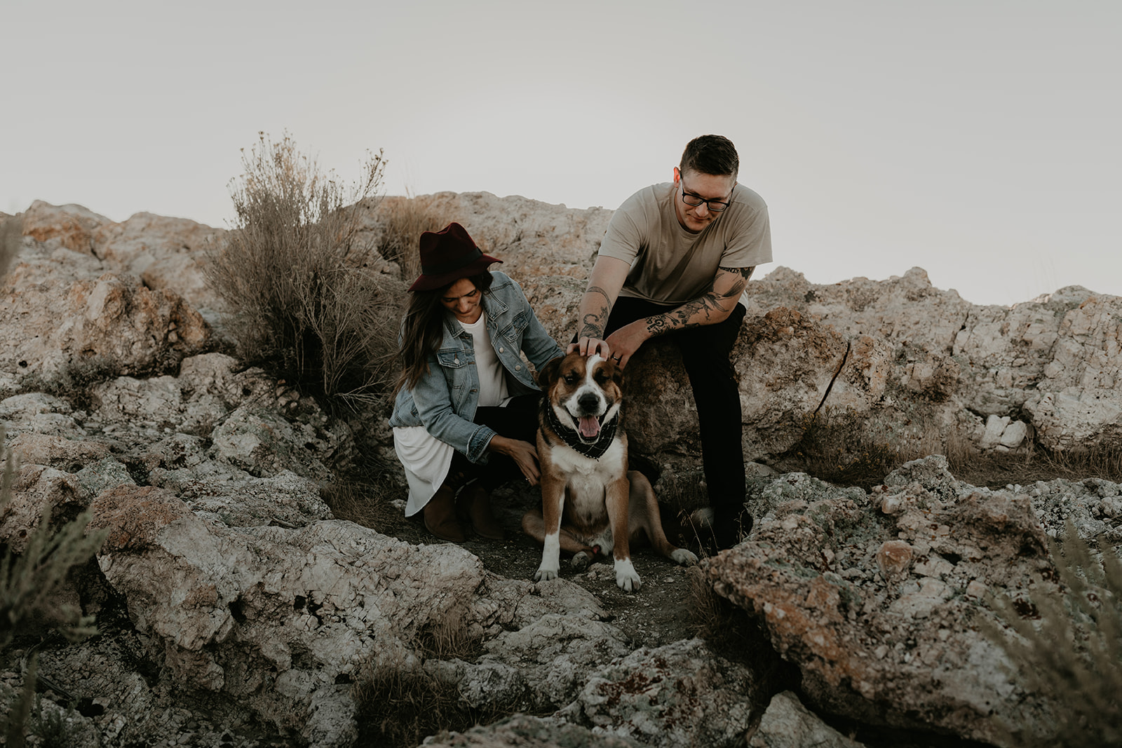 couple pose together with their dog on rocks in the beautiful Utah nature during their Engagement photos in Utah