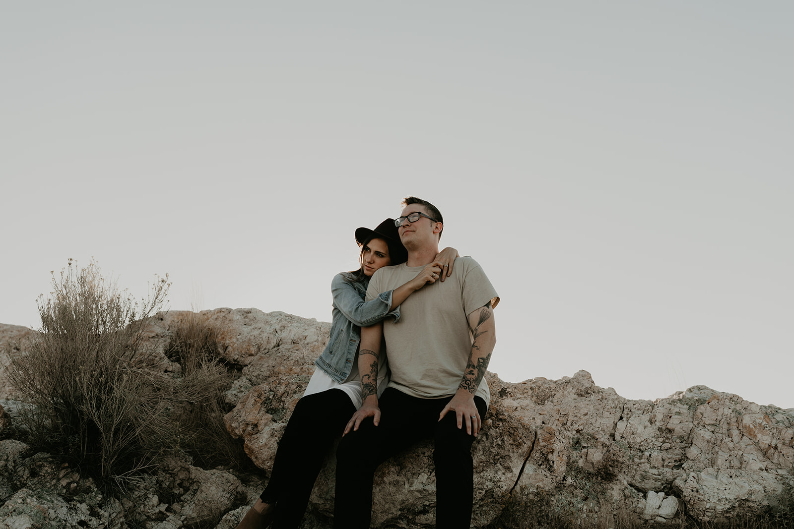 couple hug each other sitting on rocks overlooking the beautiful Utah nature 