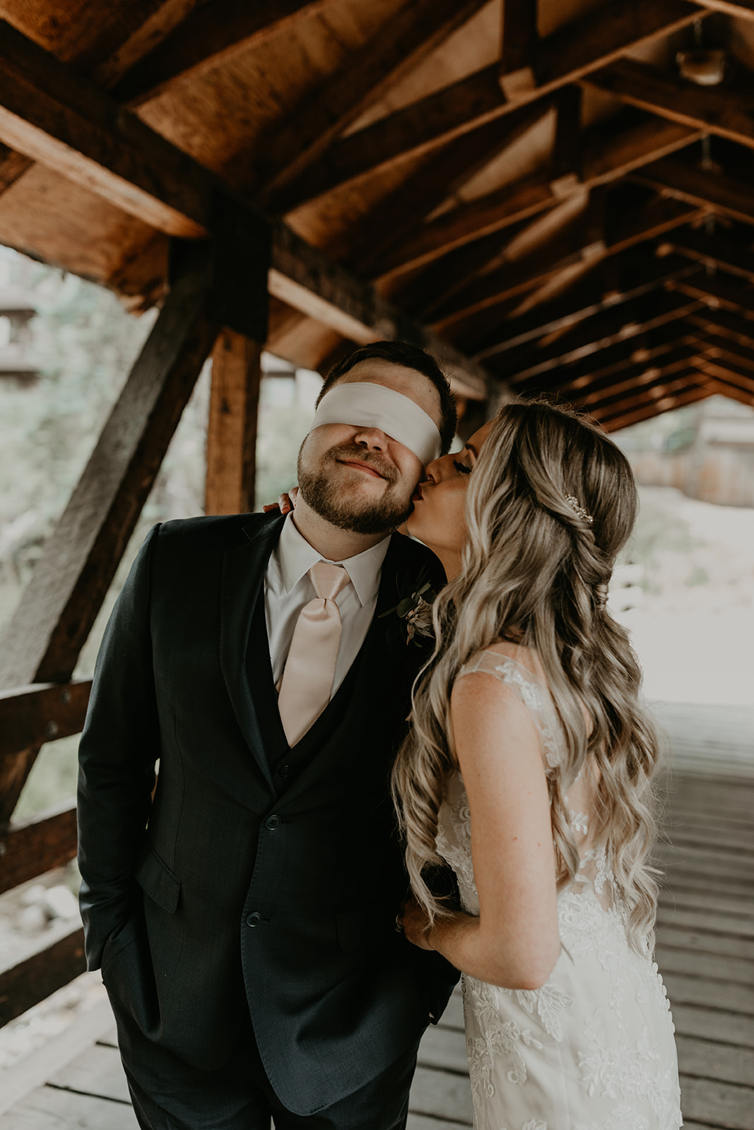 bride gives her blindfolded fiance a kiss on the cheek