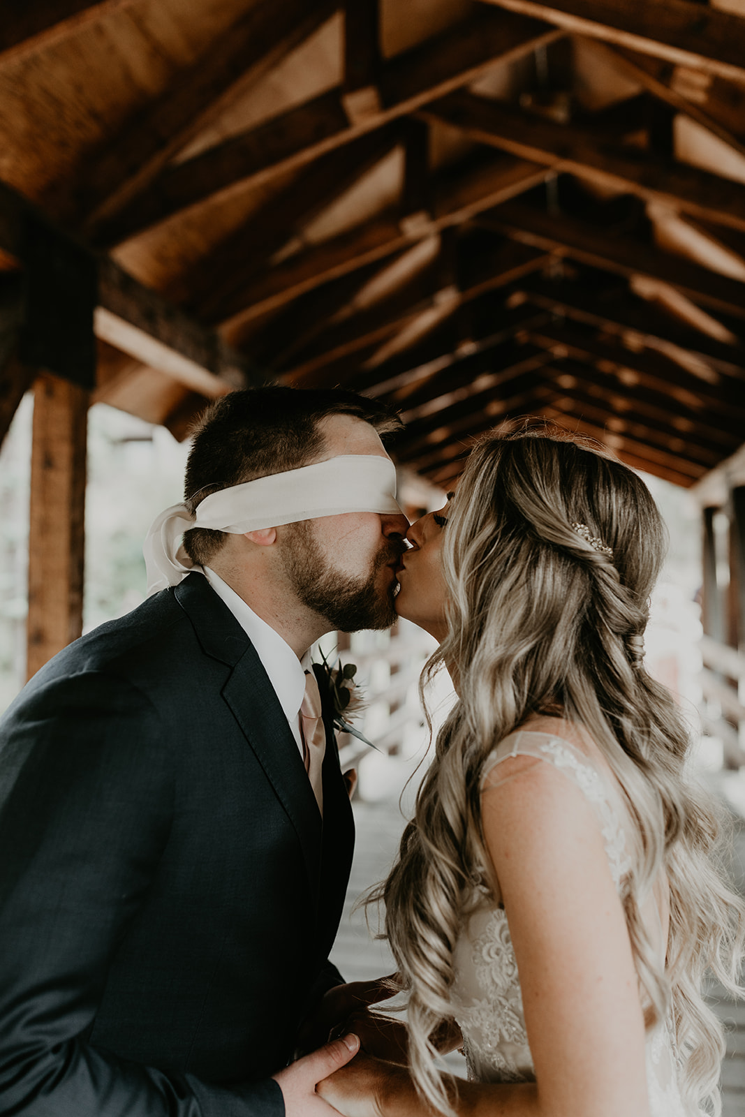 bride and blindfolded groom share a kiss during their first touch session